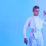 Modelo com visual futurista sob iluminação azul, em uma imagem que associa moda e tecnologia.