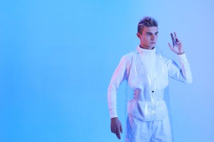 Modelo com visual futurista sob iluminação azul, em uma imagem que associa moda e tecnologia.