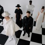 Modelos apresentam looks monocromáticos sobre um piso com padrão de xadrez em um ensaio de moda.