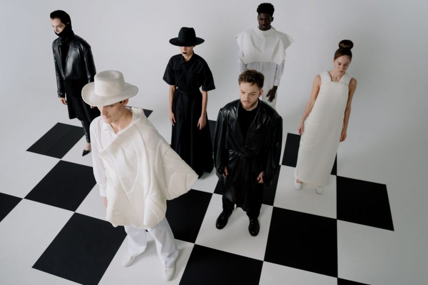 Modelos apresentam looks monocromáticos sobre um piso com padrão de xadrez em um ensaio de moda.