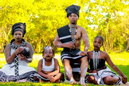 Grupo de pessoas usando trajes tradicionais Xhosa em um ambiente externo.