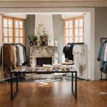 Interior de uma boutique de moda com roupas organizadas em araras e elementos de exposição.