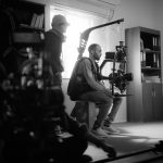 Equipe de filmagem trabalha em ambiente interno com uma câmera profissional.
