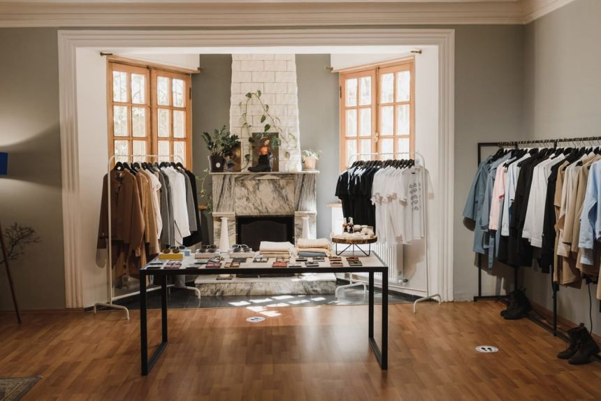 Interior de uma boutique de moda com roupas organizadas em araras e elementos de exposição.