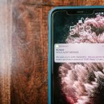 Smartphone exibindo uma notificação de alerta de fraude sobre uma superfície de madeira.