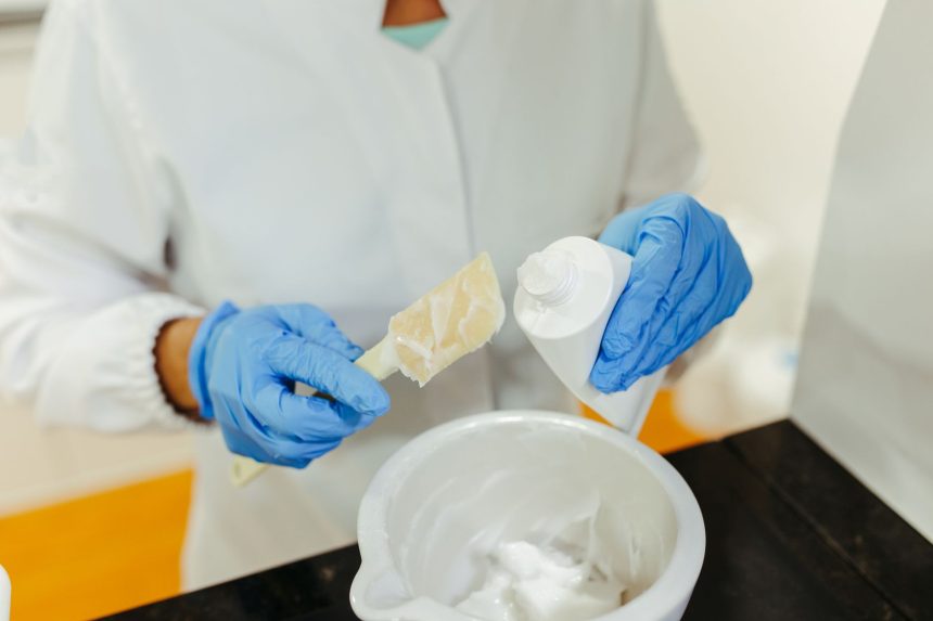 Técnico de laboratório usando luvas mistura uma formulação cremosa para pesquisa cosmética.