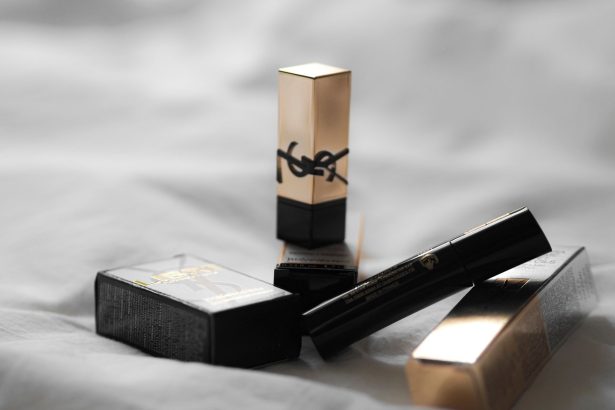 Produtos de beleza da YSL dispostos sobre um tecido claro, em composição de luxo.