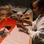 Designer de moda trabalha com retalhos de tecido em um espaço criativo interno.